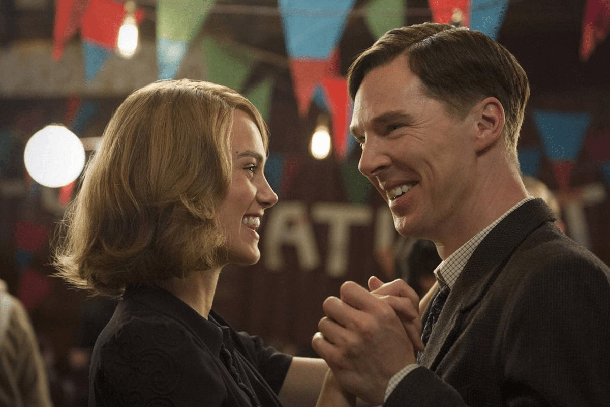 Two people dance, smiling at each other, surrounded by colorful bunting in a warmly lit room.