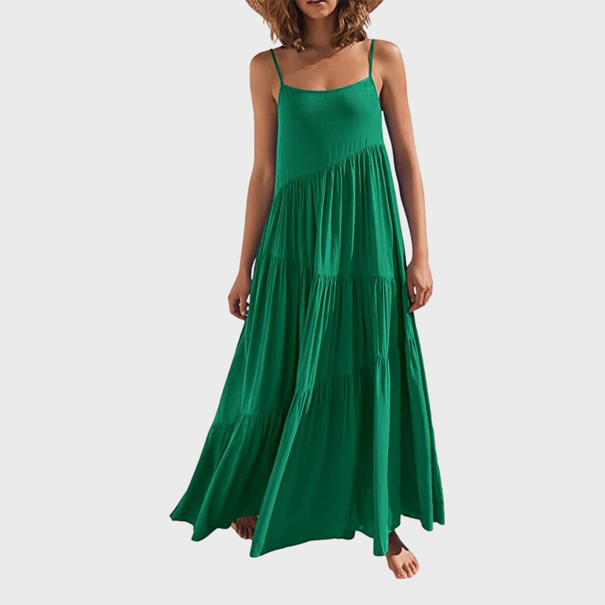 A woman wears a flowing green maxi dress, standing against a plain white background.