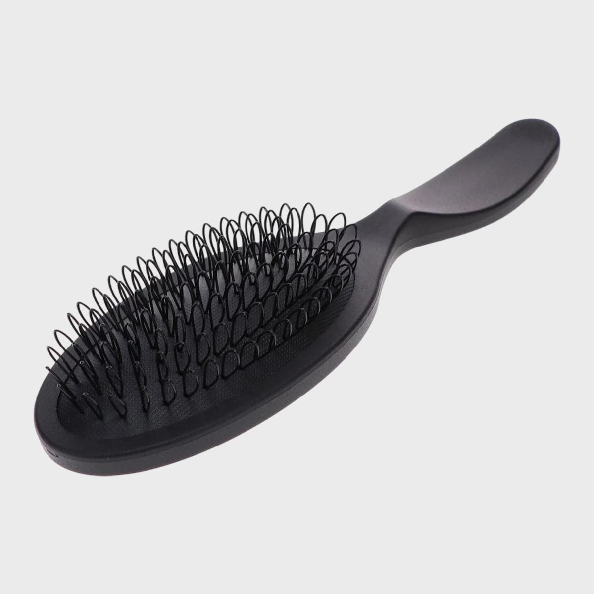Black hairbrush lying still; features looped bristles and an ergonomic handle; isolated against a plain, light gray background.