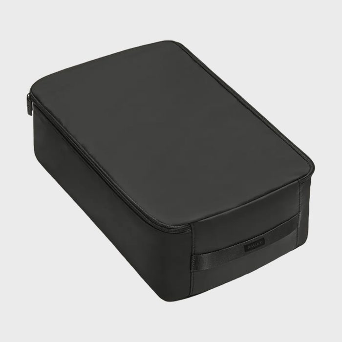 Rectangular black travel pouch sits on a light gray background, featuring a zipper and a small label reading 