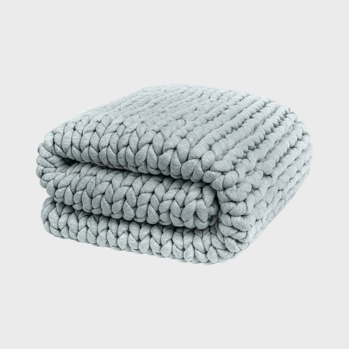 A thick, light gray knitted blanket is folded neatly against a plain white background.