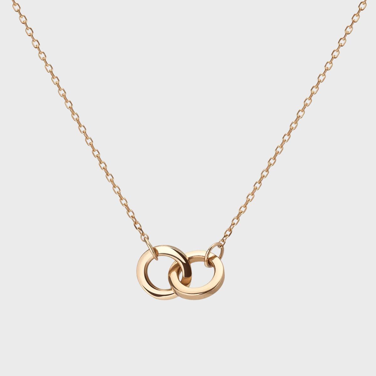 Gold necklace featuring two interlinked rings, centered, on a plain white background.