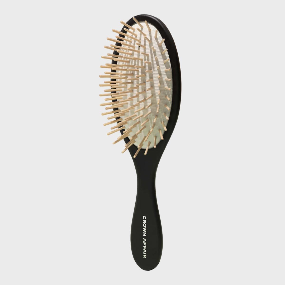 Brush with wooden bristles resting against a plain background; printed text reads "CROWN AFFAIR" on the handle.