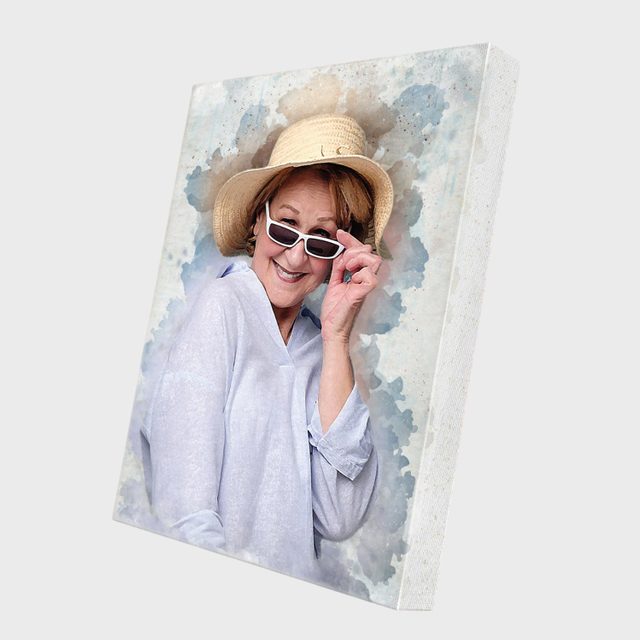 Woman smiling, adjusting sunglasses, wearing a straw hat against a watercolor-style background on a canvas print.