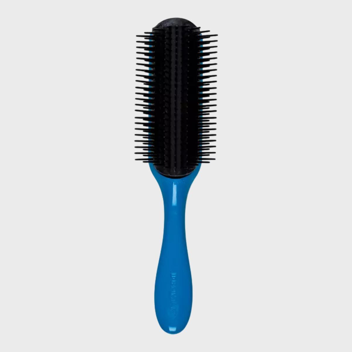 A blue-handled brush, with black bristles, rests vertically against a plain gray background.