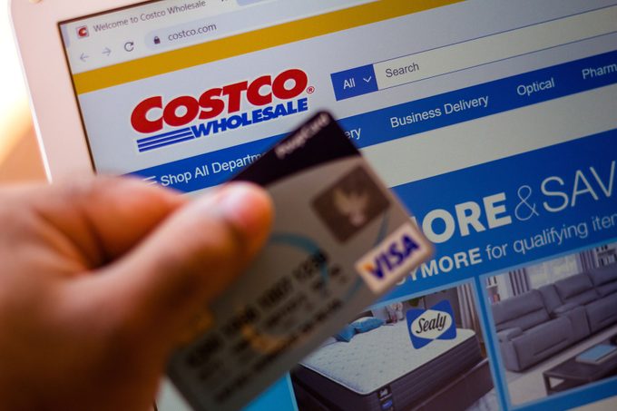 The Costco Wholesale Corporation Website Is Displayed On A Laptop Computer Screen with a person holding a visa card in front of it