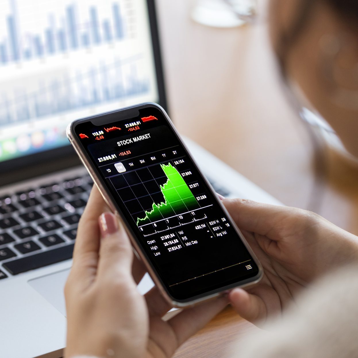 Young finance expert analyzing financial charts on smart phone