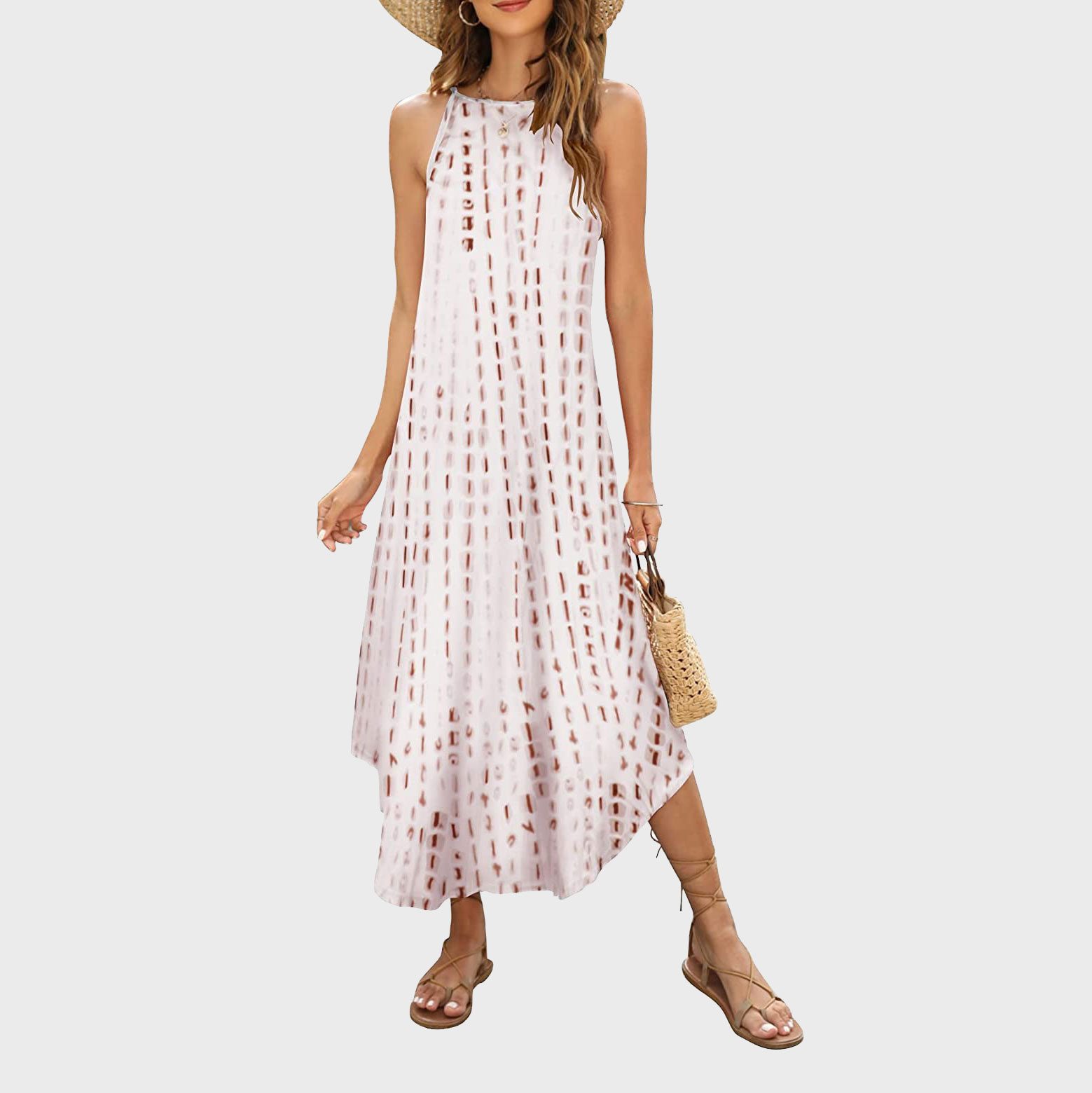 A woman in a patterned sundress and sandals poses with a woven bag against a plain background.