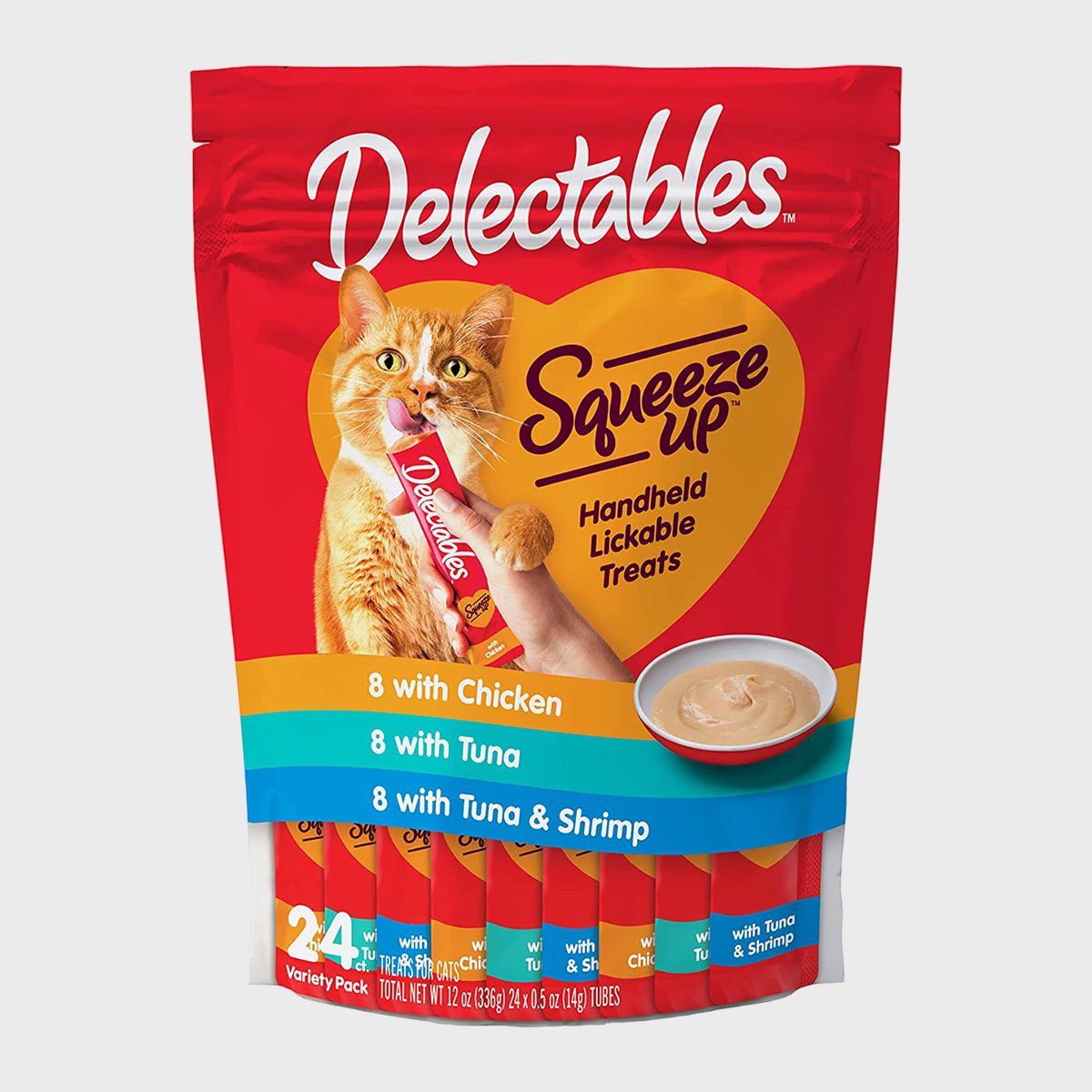 Cat enjoys lickable treat, held by a hand, against a red and yellow package with text detailing chicken, tuna, and shrimp flavors.