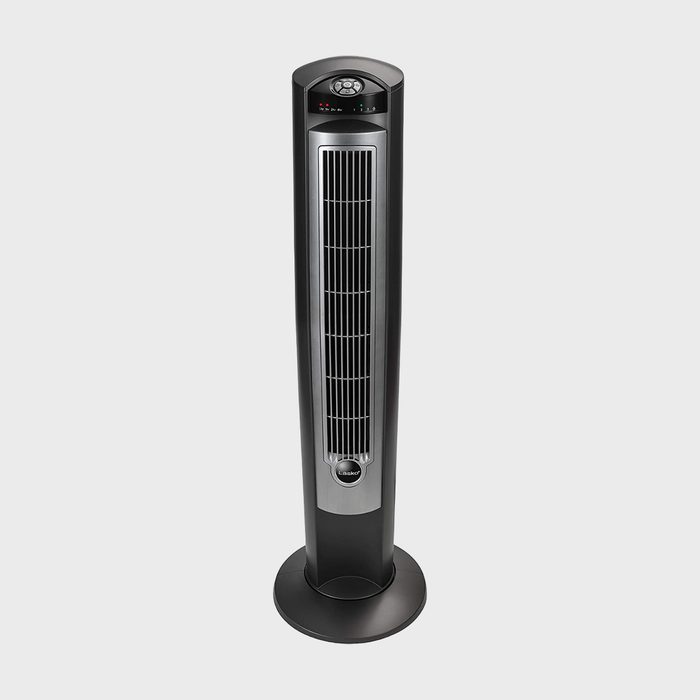 A black tower fan stands on a flat surface displaying control buttons and indicators on a digital panel on top.
