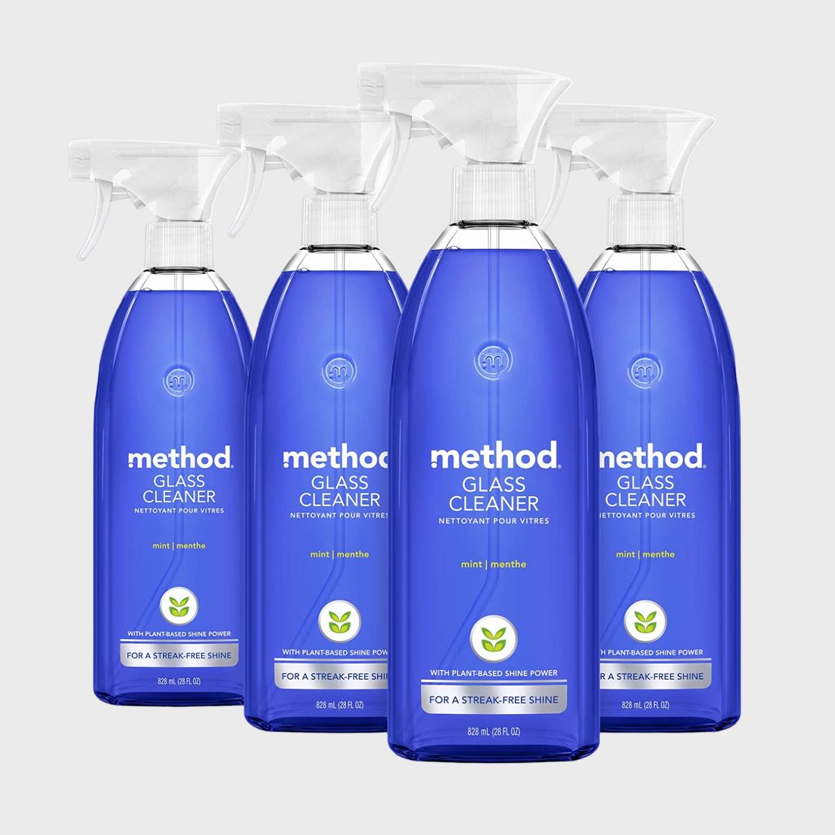 Bottles labeled "method Glass Cleaner" stand upright, featuring mint scent, against a plain background, showcasing plant-based shine power and streak-free promise.