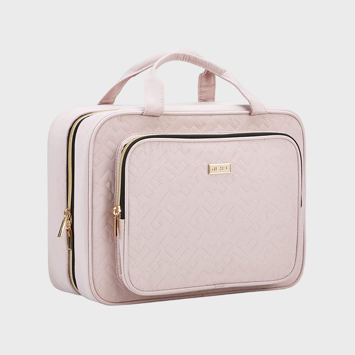 Light pink quilted handbag with gold zippers and a small front pocket sits on a plain white background.
