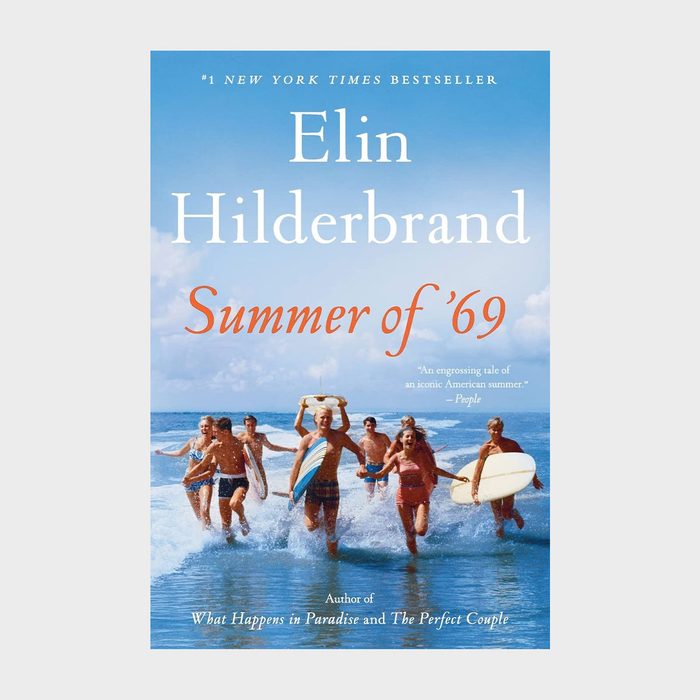 Group running, carrying surfboards, through shallow water; text reads 