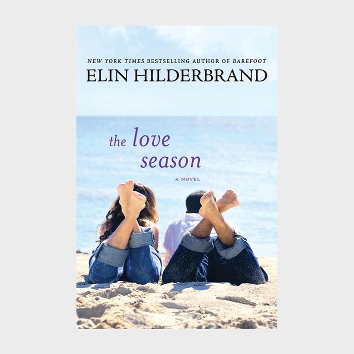 Two people lie on a sandy beach with their feet up, facing a calm sea under a clear sky. Text: 