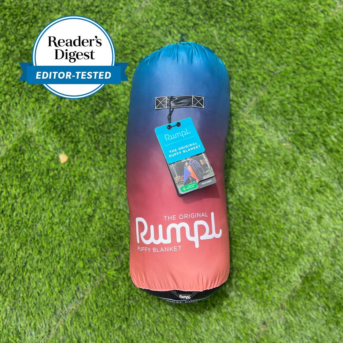 Blanket, rolled and tagged, lies on grass; it's labeled "The Original Rumpl Puffy Blanket," featuring a gradient design. Reader's Digest Editor-Tested badge included.