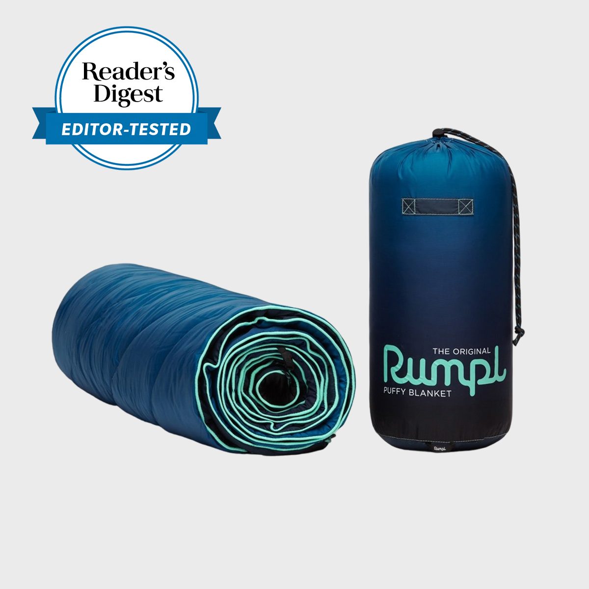 A rolled blue blanket next to its cylindrical storage bag, labeled "Rumpl Puffy Blanket," with a "Reader's Digest Editor-Tested" badge in the corner.