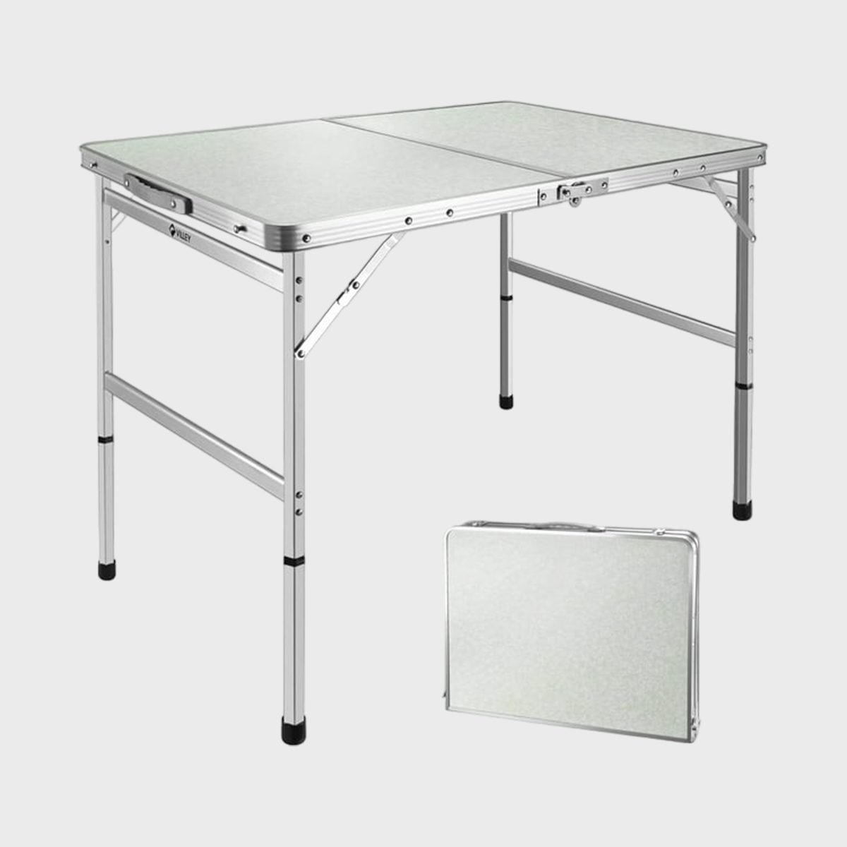 A silver foldable table stands upright, shown in an indoor studio with a small folded version beside it, highlighting its portable feature.
