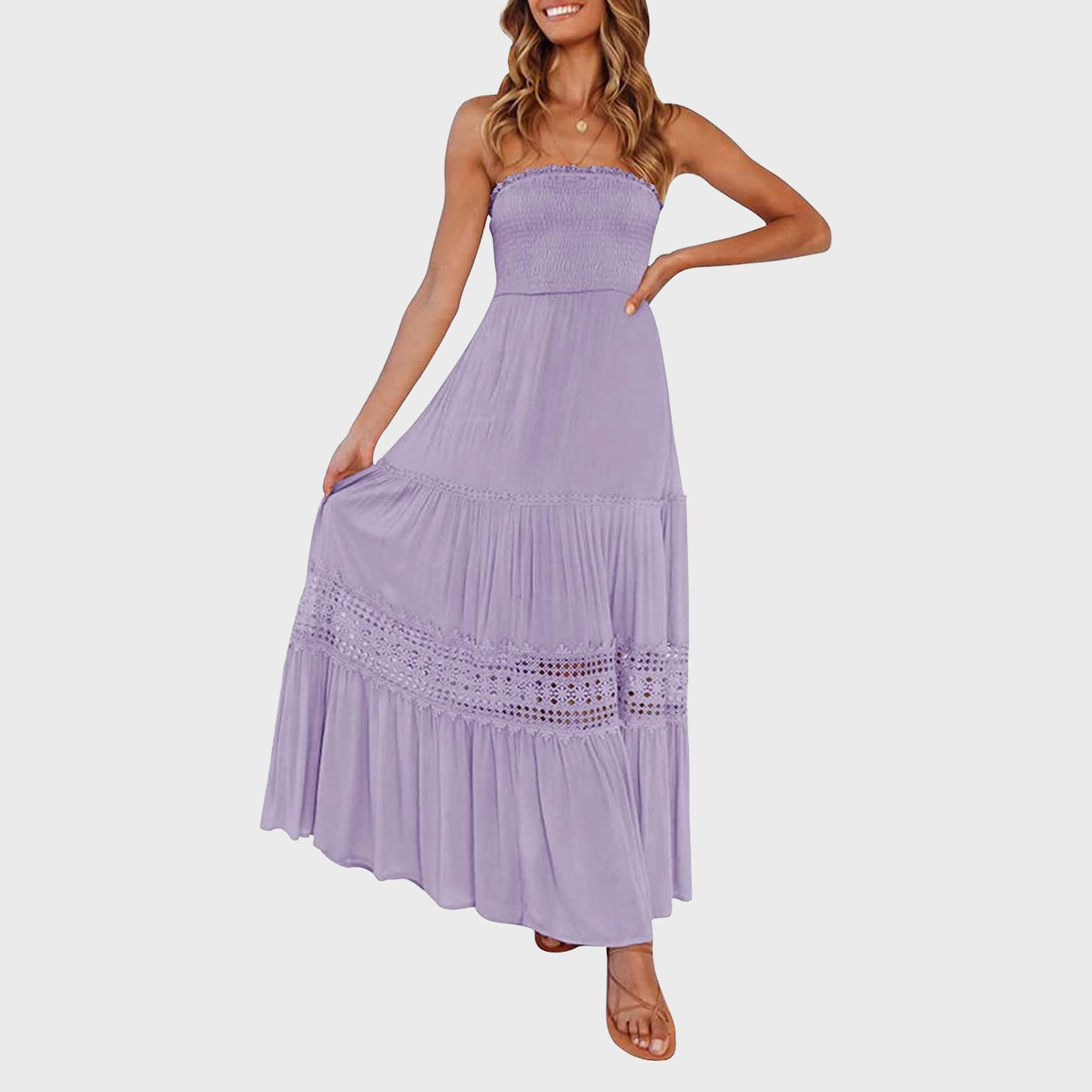 A person wears a lavender strapless maxi dress, holding its hem, standing against a plain white background.