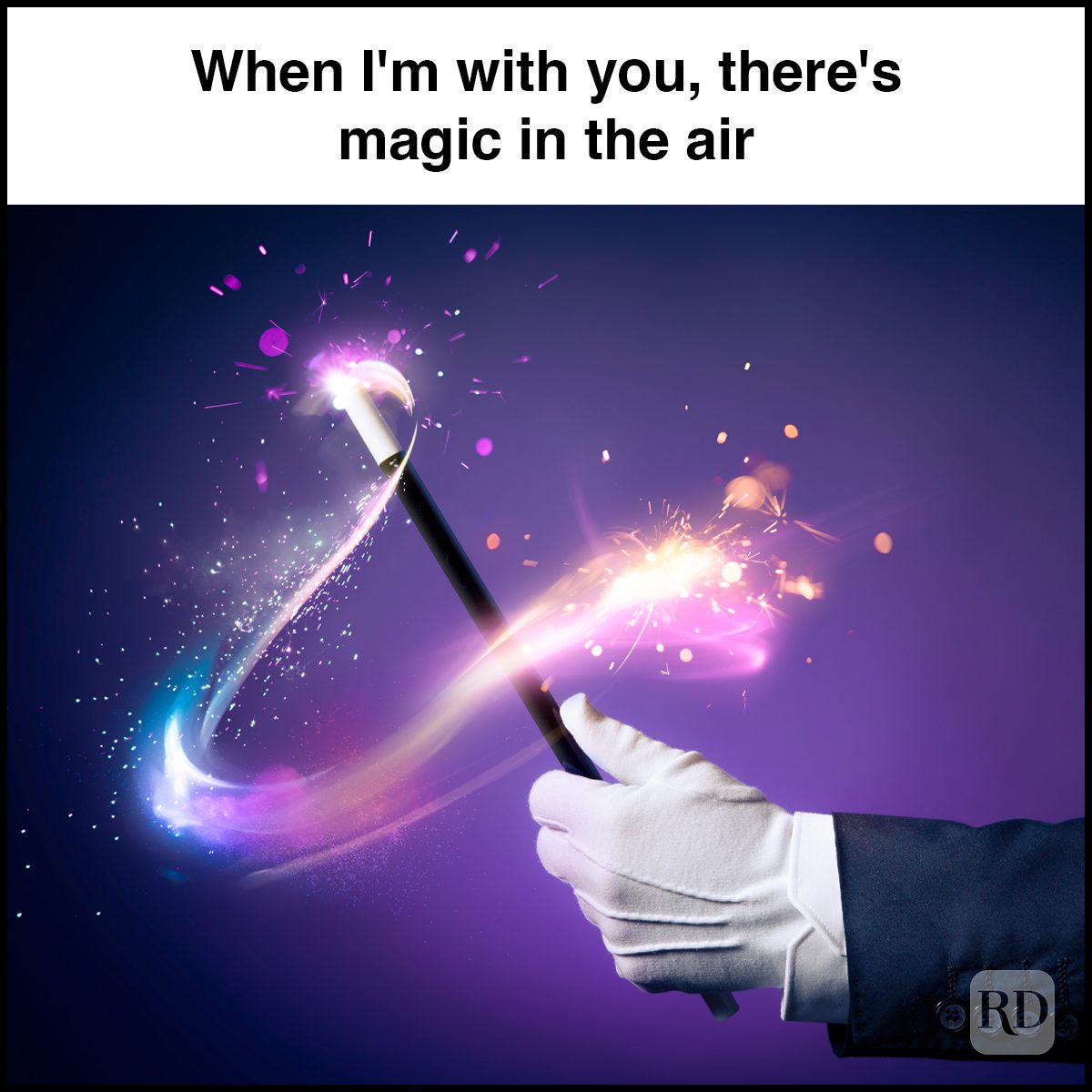 A gloved hand wields a magic wand emitting colorful sparks and trails against a dark background. Text reads, "When I'm with you, there's magic in the air."