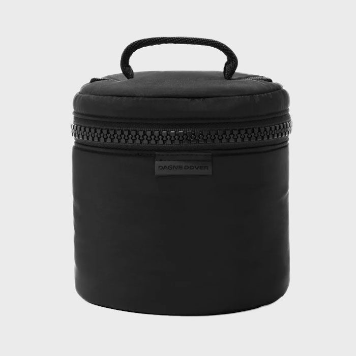 A black cylindrical bag with a handle, featuring a zipper. Label reads 