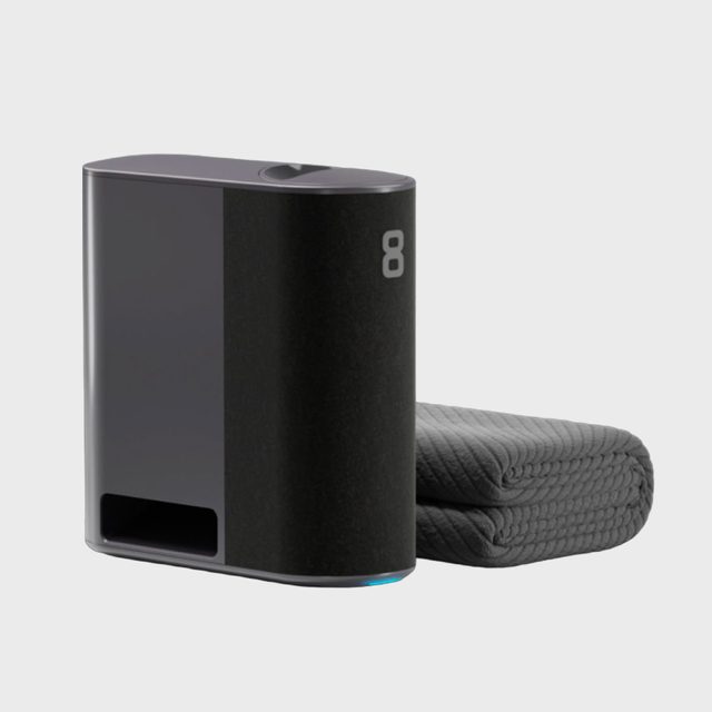 A rectangular black device sits beside a folded textured gray blanket on a light background. Number 
