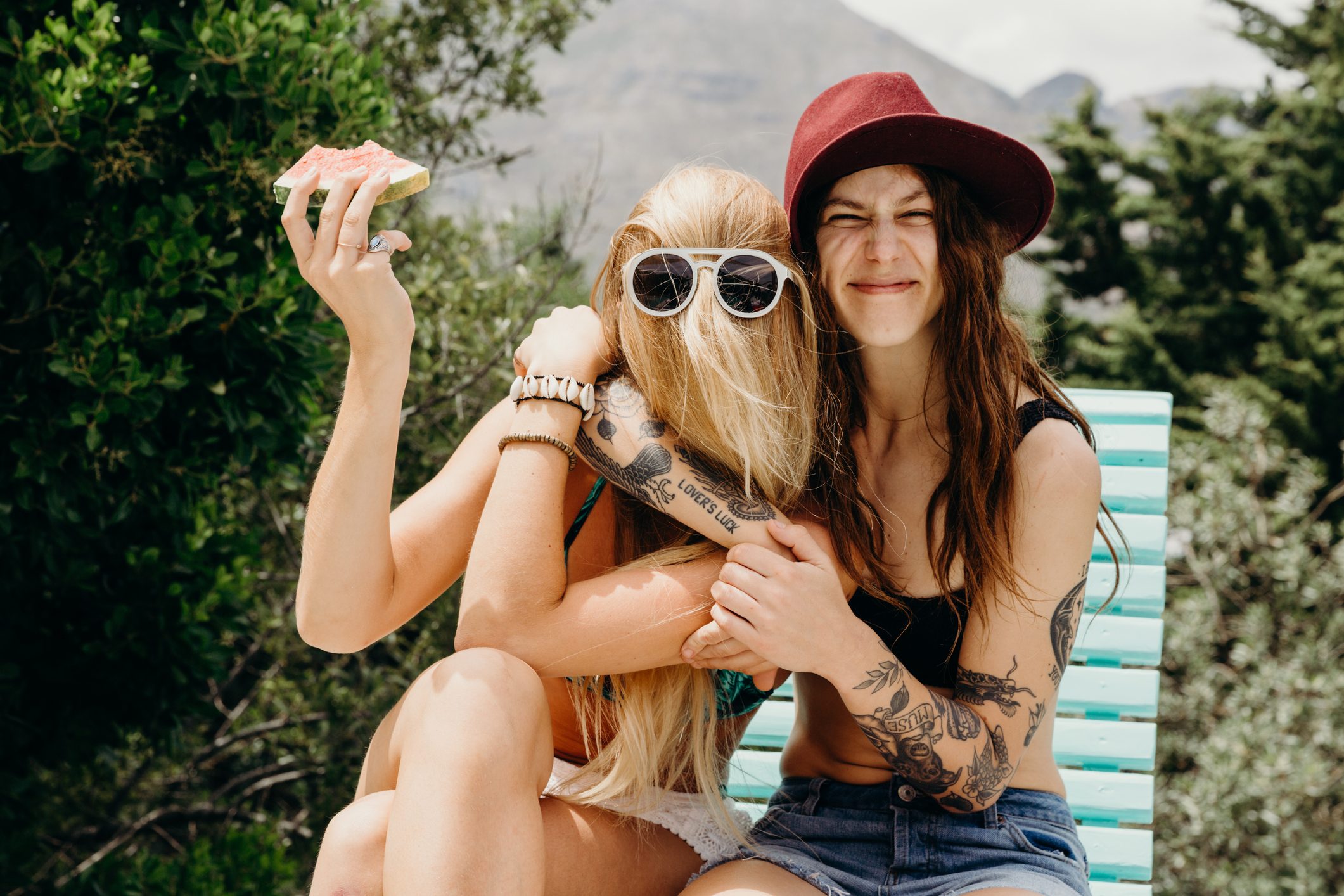 Happy oddball girlfriends embrace outdoors with watermelon in hand