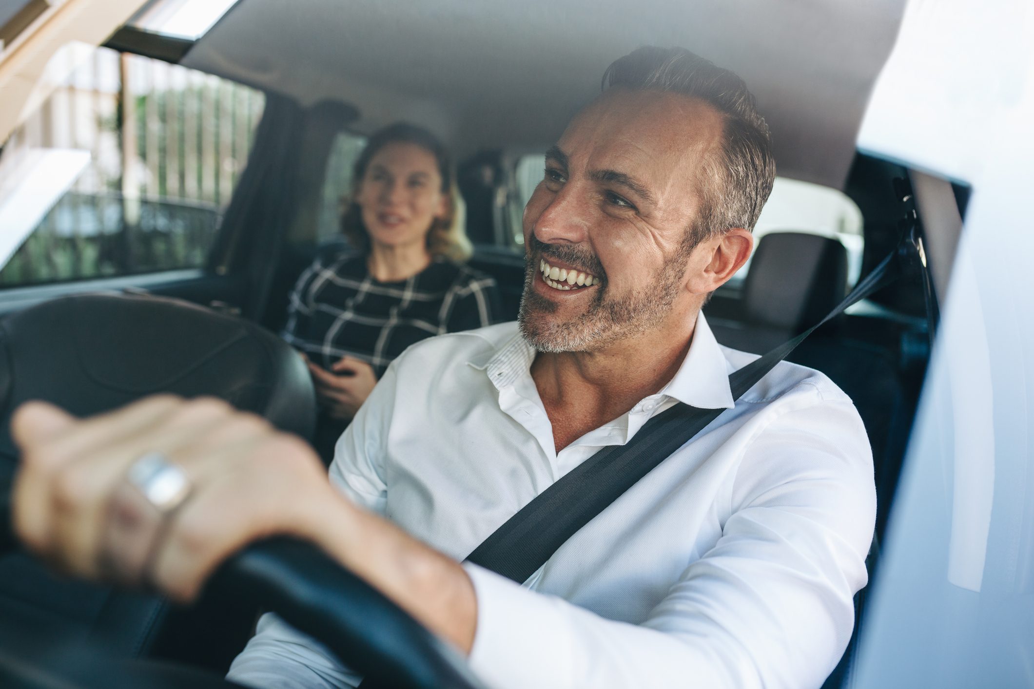 Taxi driver talking to a female passenger in car
