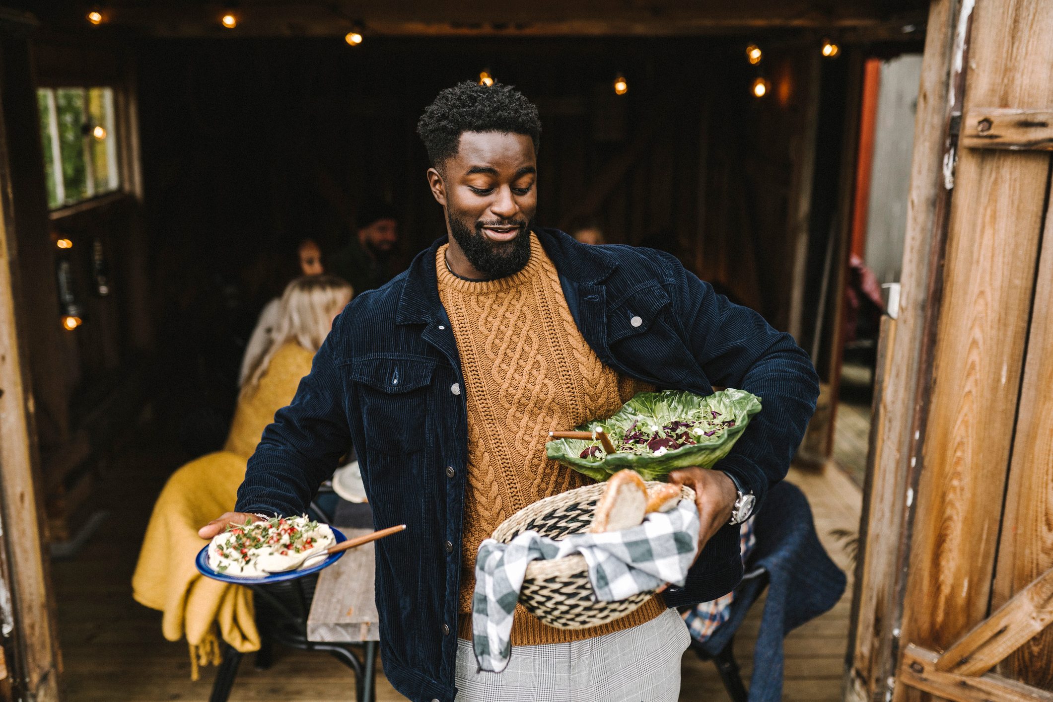 Smiling man balancing food while standing at doorway during social gathering