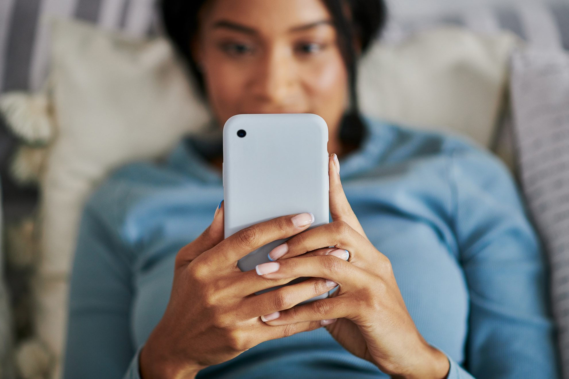 Shot of a young woman using a phone at home