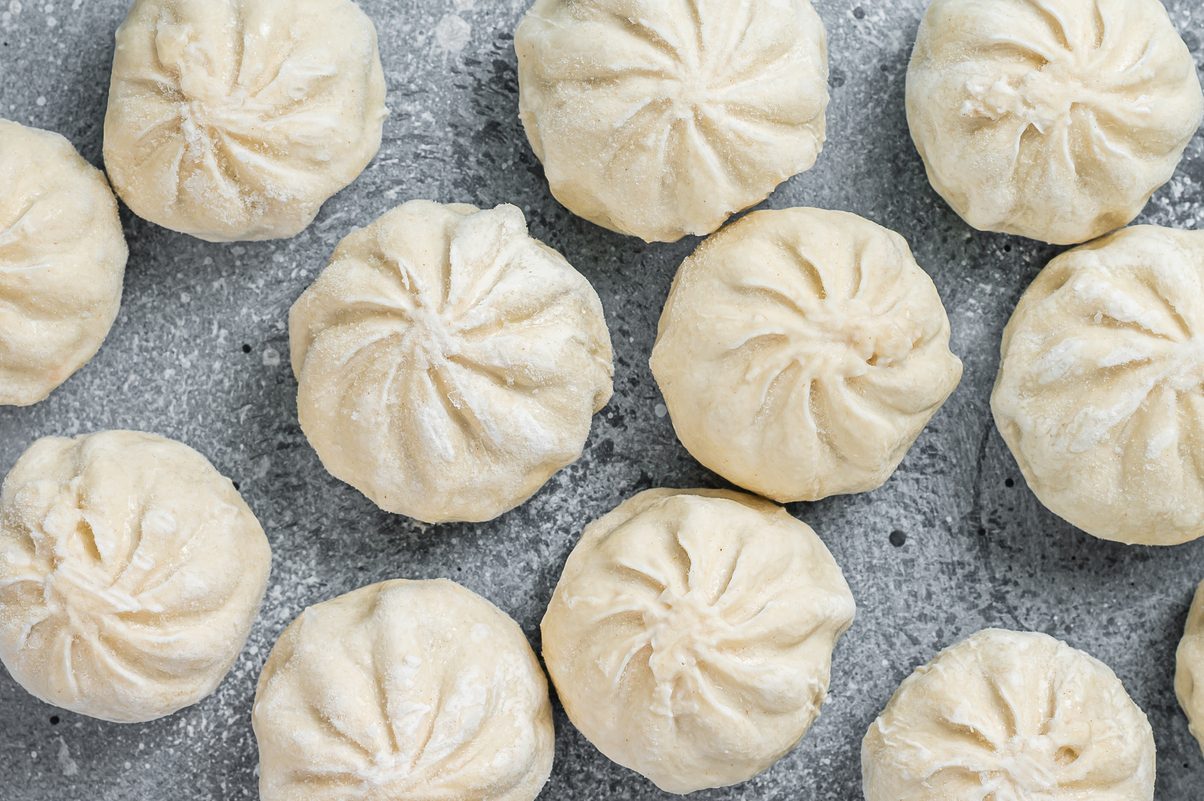 Frozen uncooked baozi dumplings stuffed with meat. Gray background. Top view