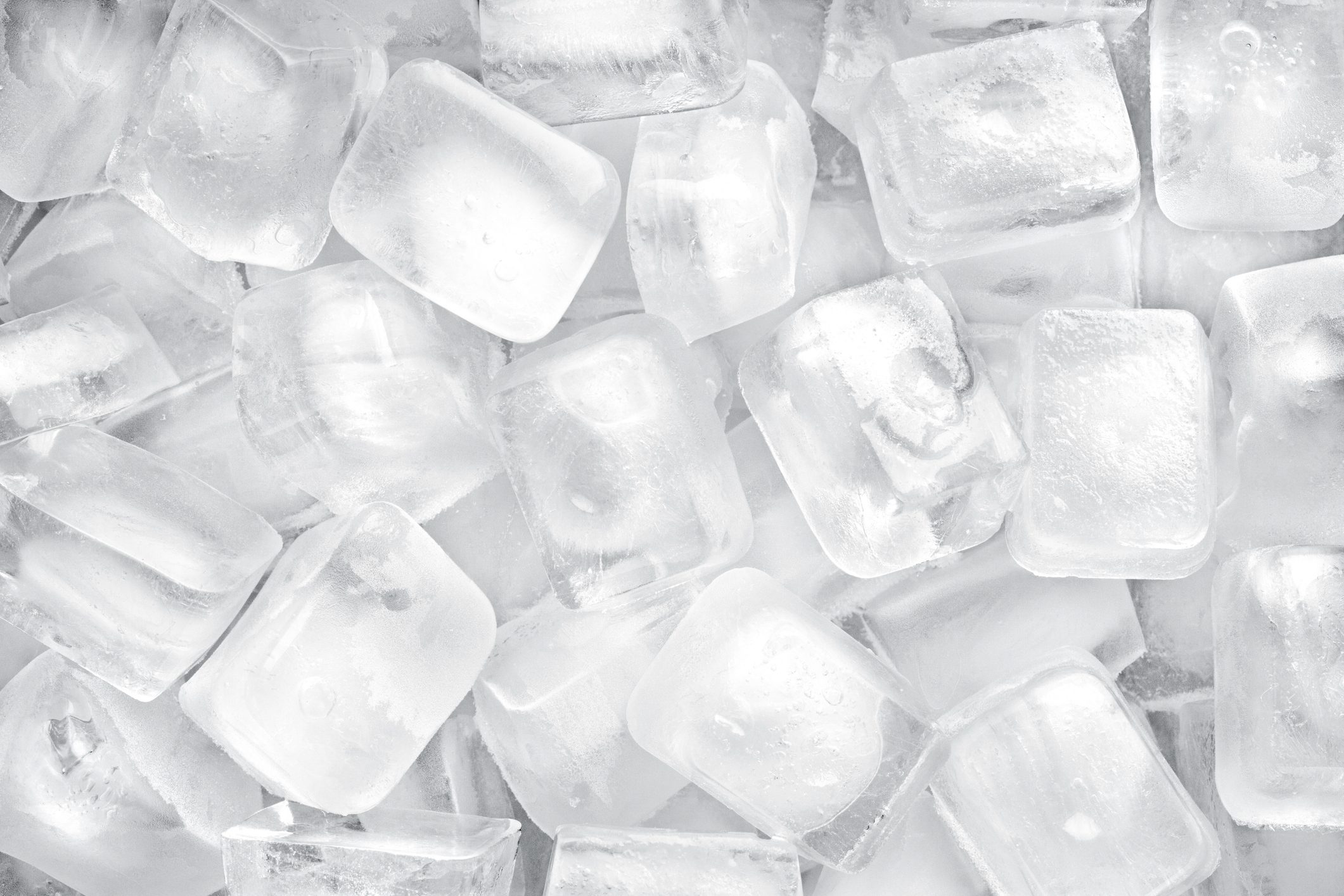 Ice cubes resting closely together, creating a textured surface of clear and frosty squares.