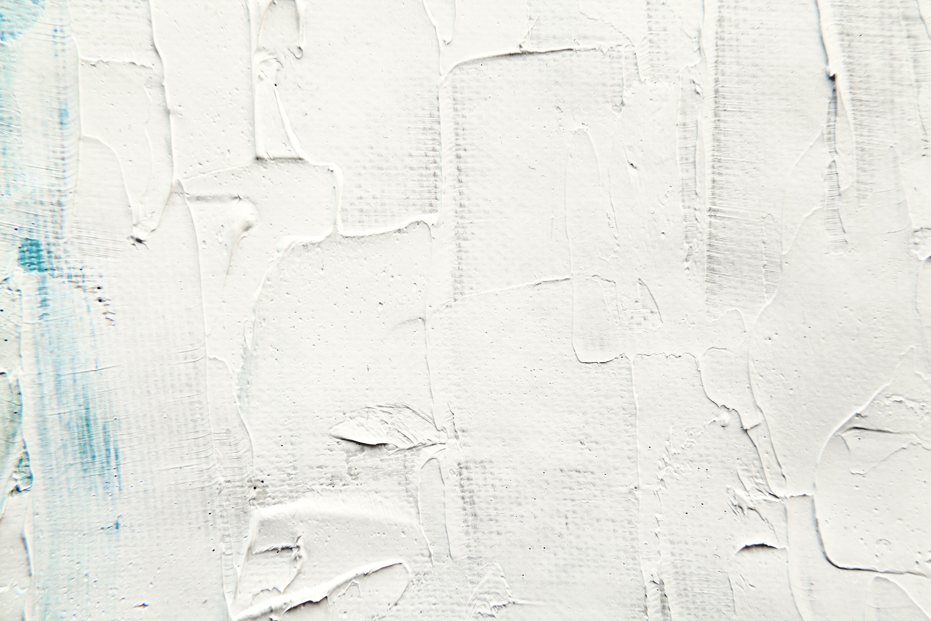 Textured white paint appears smeared across a canvas with hints of blue, creating an abstract pattern.