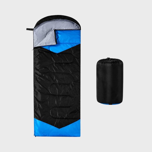 Sleeping bag lies open with blue and gray lining, next to a compact black carrying sack, against a plain background.