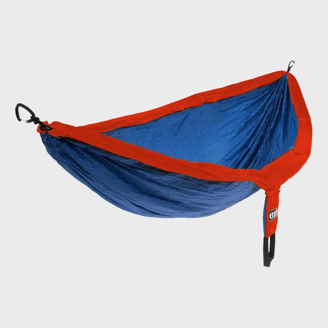A blue and red hammock is suspended in mid-air with black clips, set against a plain gray background.