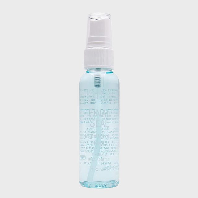 A transparent bottle containing blue liquid with a white spray nozzle, standing upright against a plain gray background.