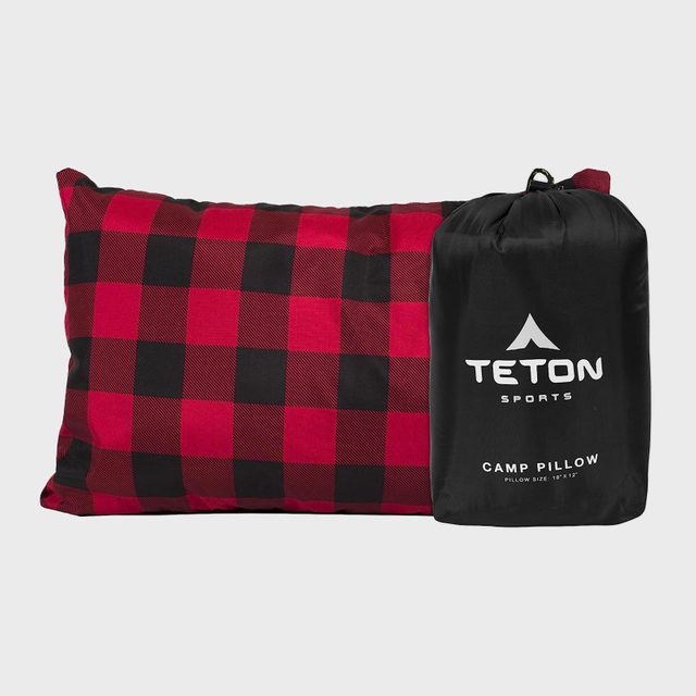 A plaid pillow lies next to a black bag. The bag reads 