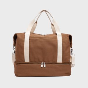 Brown canvas duffel bag displaying white handles and shoulder strap against a plain background.