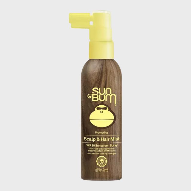 Bottle sprays sunscreen mist, featuring yellow nozzle and logo on a wood-patterned backdrop, labeled 