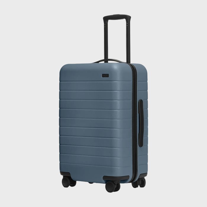A blue suitcase with wheels stands upright, featuring an extended handle and horizontal ridges, set against a plain white background.