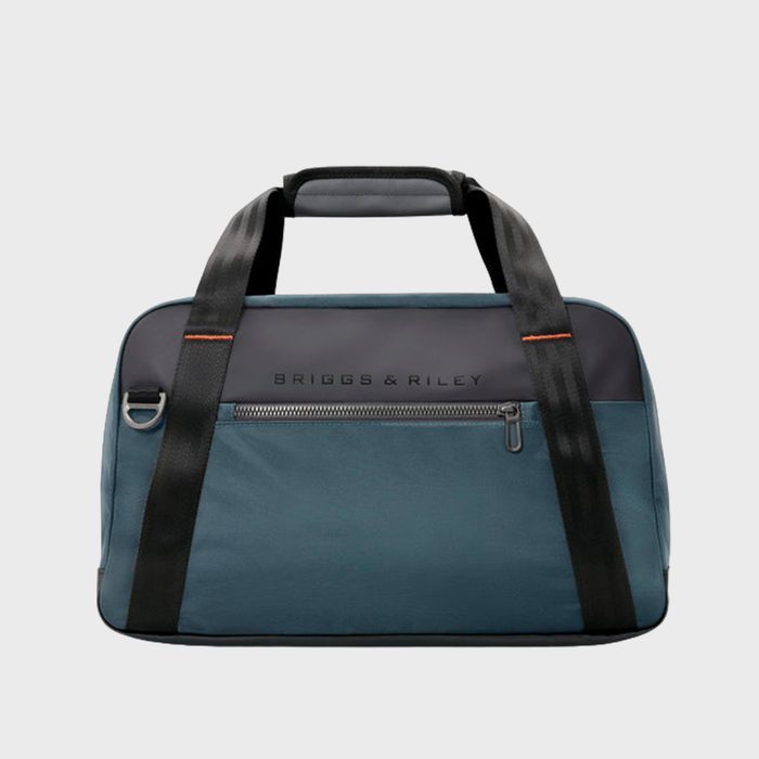 A teal travel bag sits with black handles and a front zipper pocket, featuring 