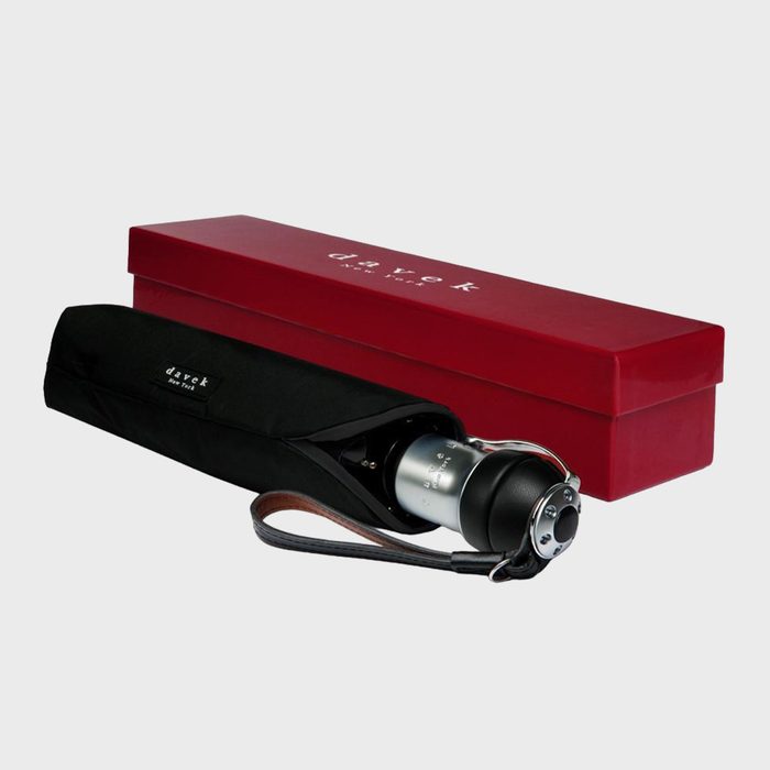 Umbrella rests inside a branded black sleeve with strap, beside a closed red box on a white background. Box reads 