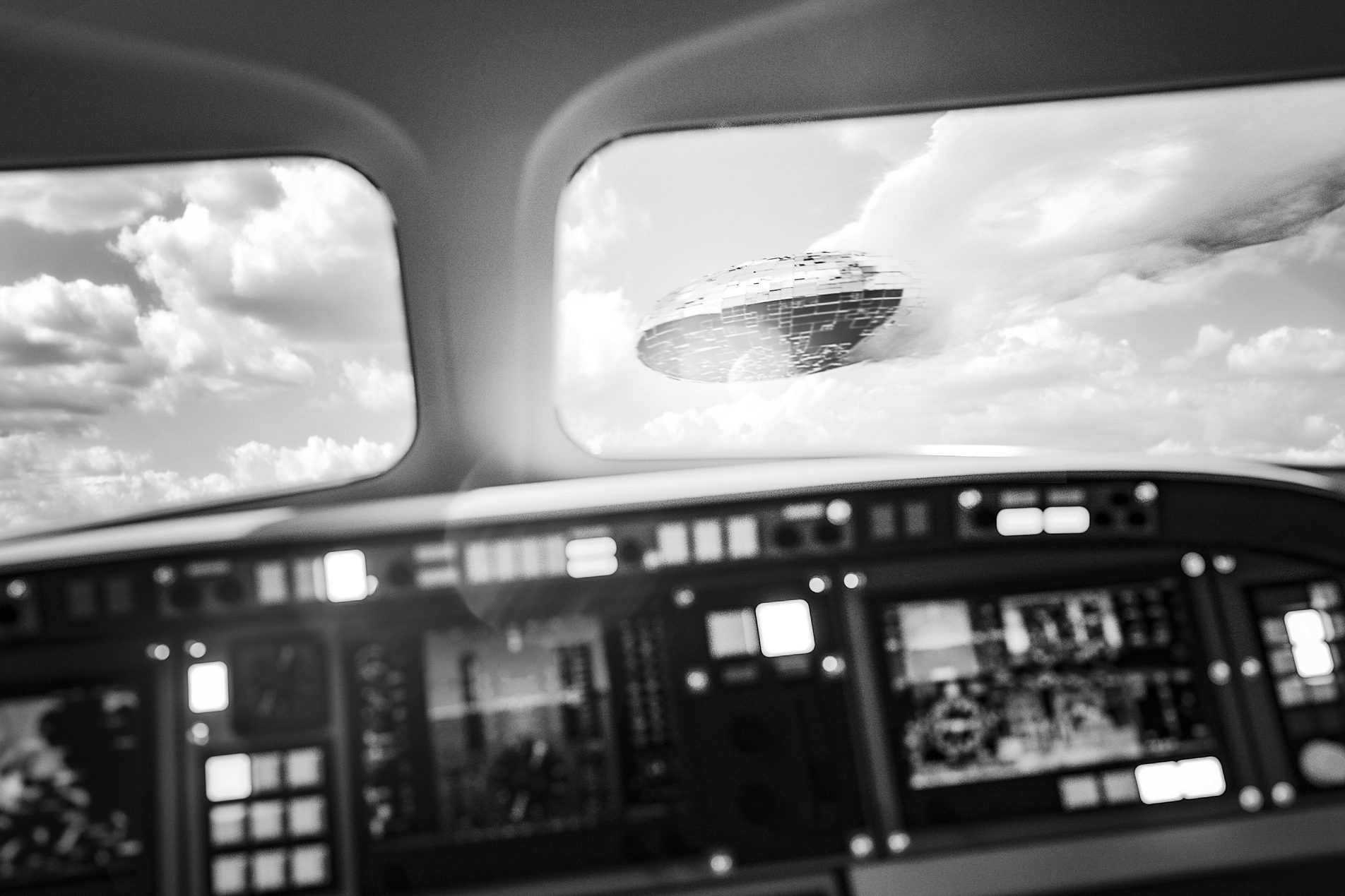 Cockpit displays blurry, unidentified flying object visible through windows, hovering in a cloudy sky.