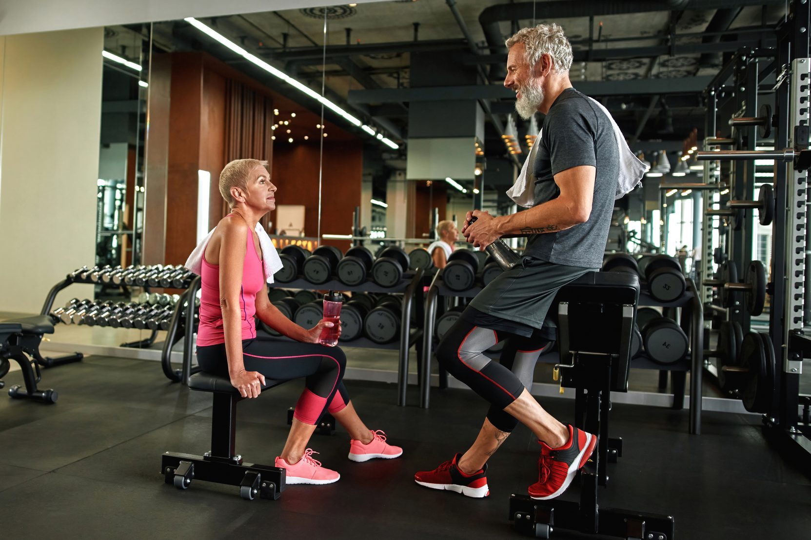 Mature man flirting with elder woman in gym