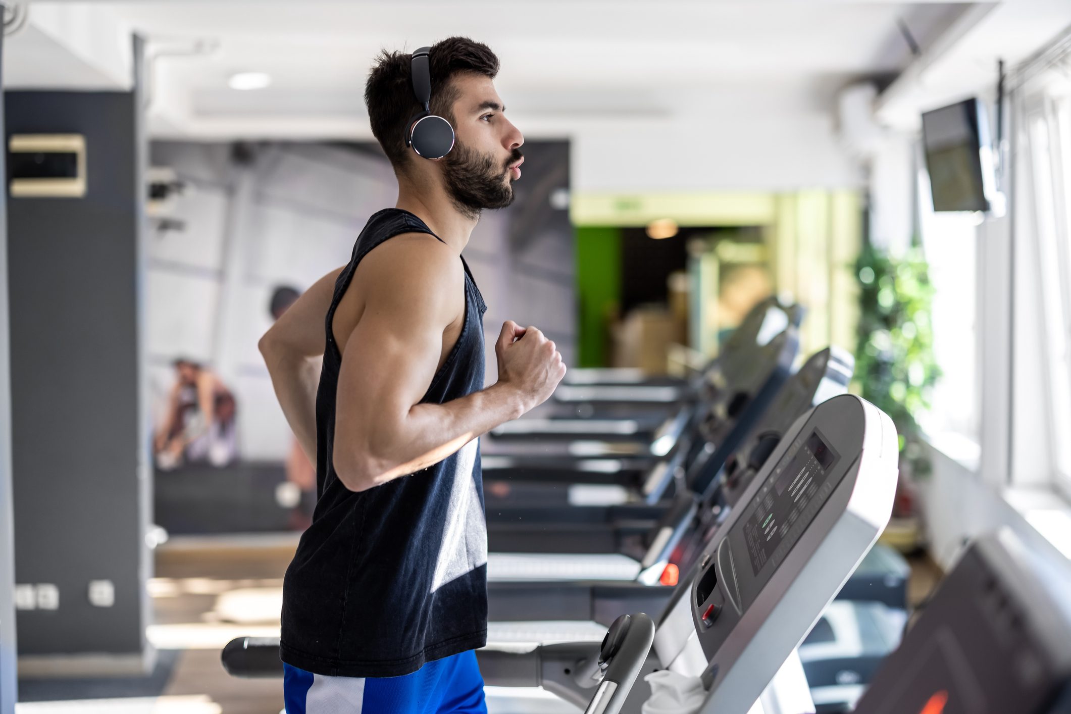 A young man is running on a treadmill in a gym.