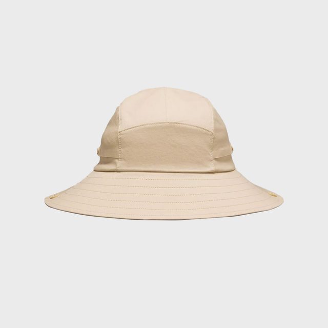 Beige bucket hat lying flat against a plain white background, displaying its wide brim and simple stitching details.