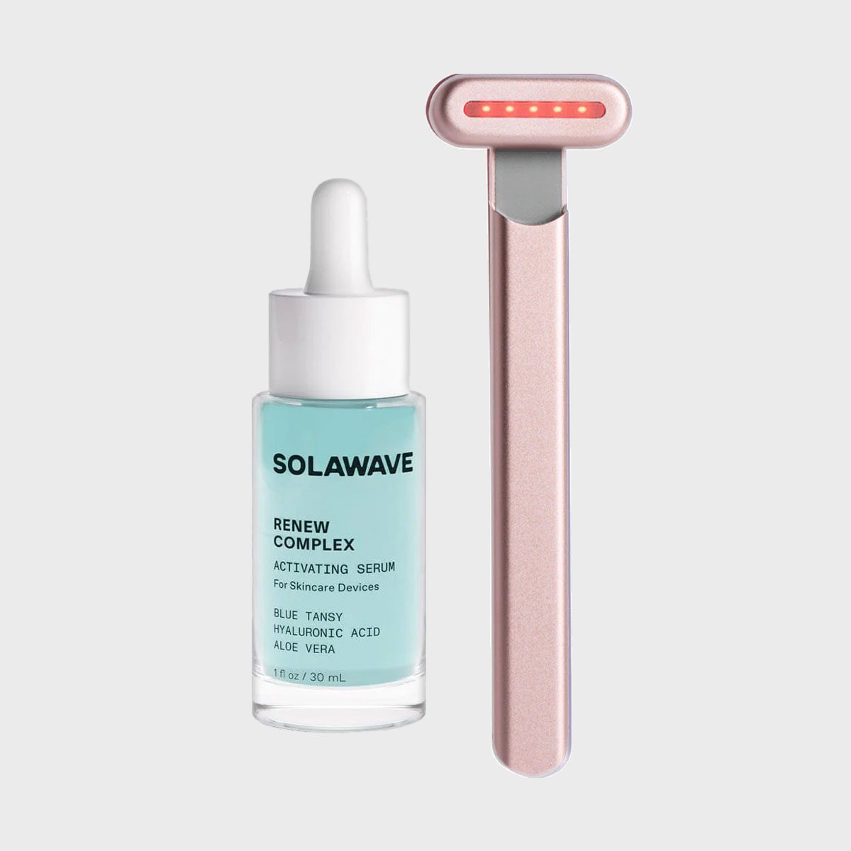 Serum bottle labeled "SOLAWAVE Renew Complex" with skincare ingredients next to a pink LED skincare device on a gray background.