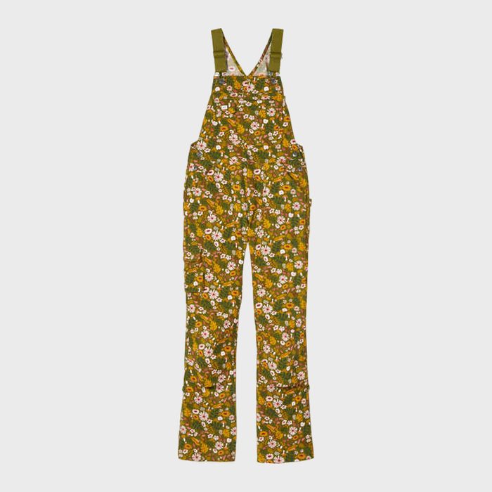 Overalls featuring floral print rest flat against a plain white background, showcasing colorful flowers in green, yellow, and orange hues.