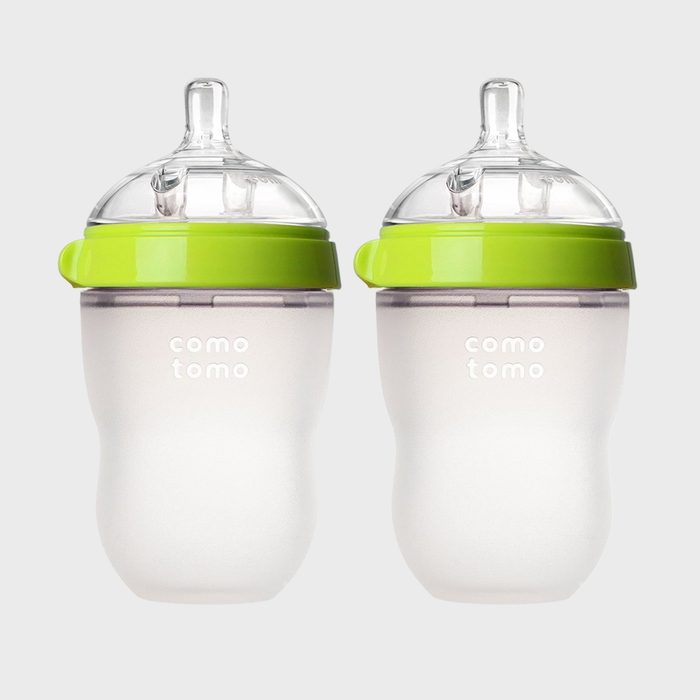 Two baby bottles with green lids are standing side by side on a plain background, displaying the text 