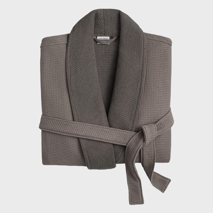 A folded gray bathrobe rests against a plain backdrop. A tag reads 