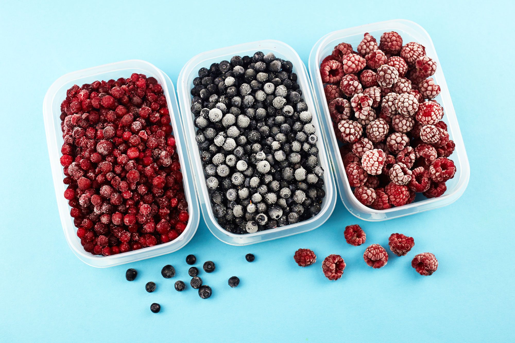 Containers hold frozen berries arranged on a light blue background.